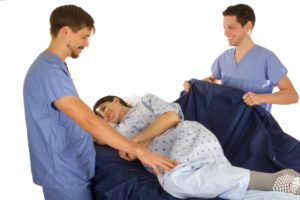 Two caregivers turn a patient with Slide Sheets