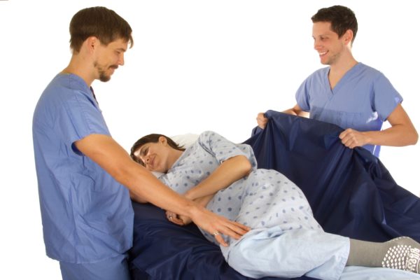 Caregiver using a MedCo Technology Slide Sheet to turn a patient