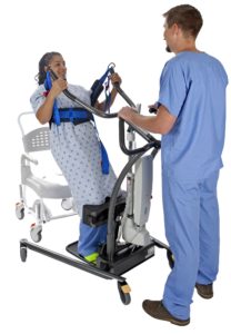 Caregiver is raising a patient to standing from a commode using a sit to stand lift